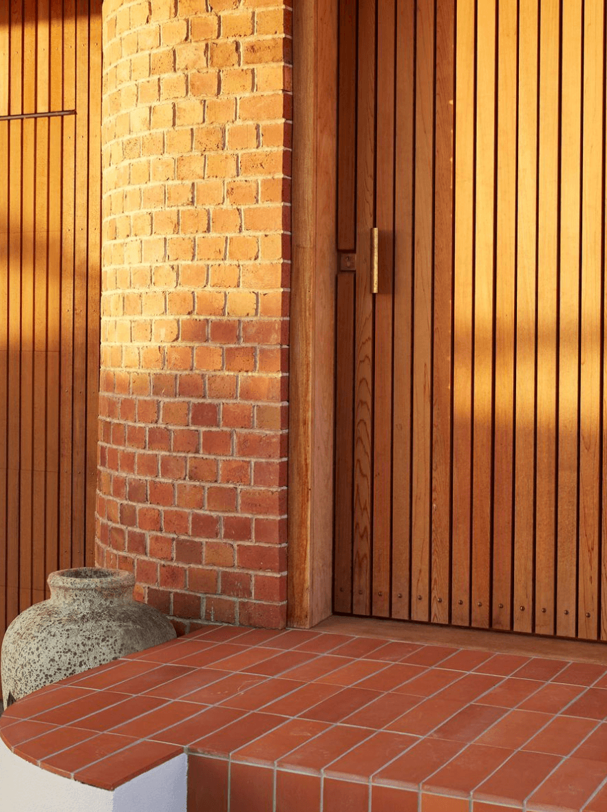 Clay terracotta tiles on the stairs with vertical timber cladding and a weathered stone urn
