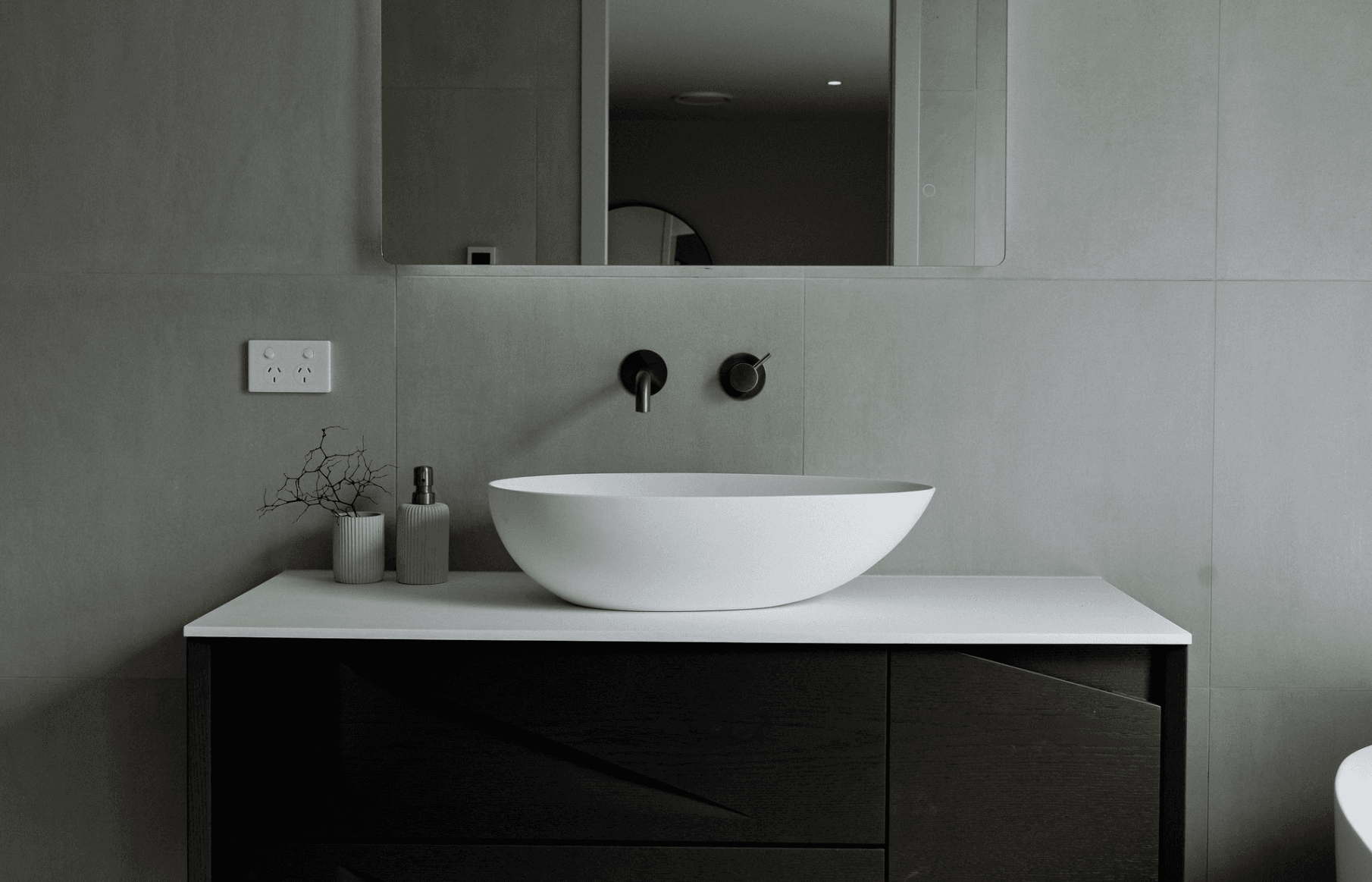 Minimalist modern bathroom with gray tiles and white vessel sink on black vanity