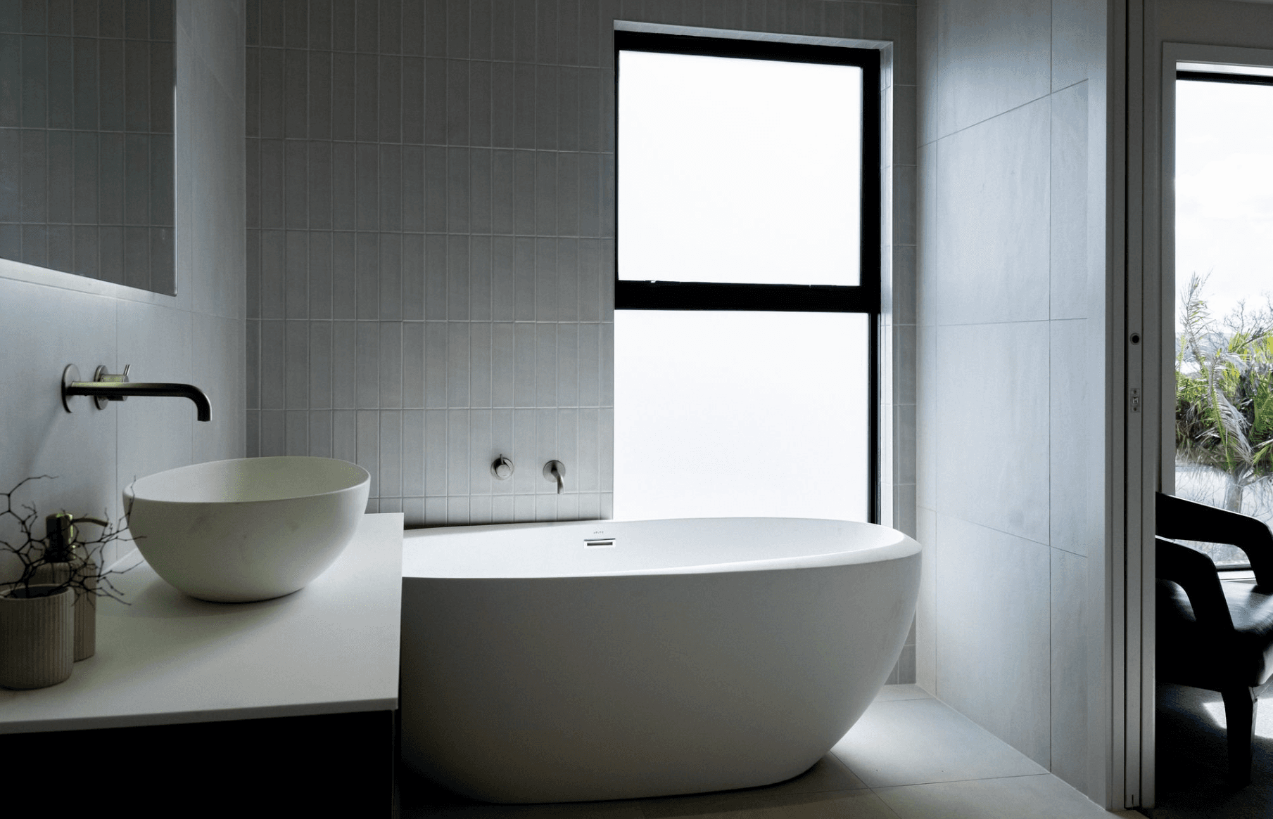 Contemporary bathroom with vertical gray tiles and freestanding tub by frosted window