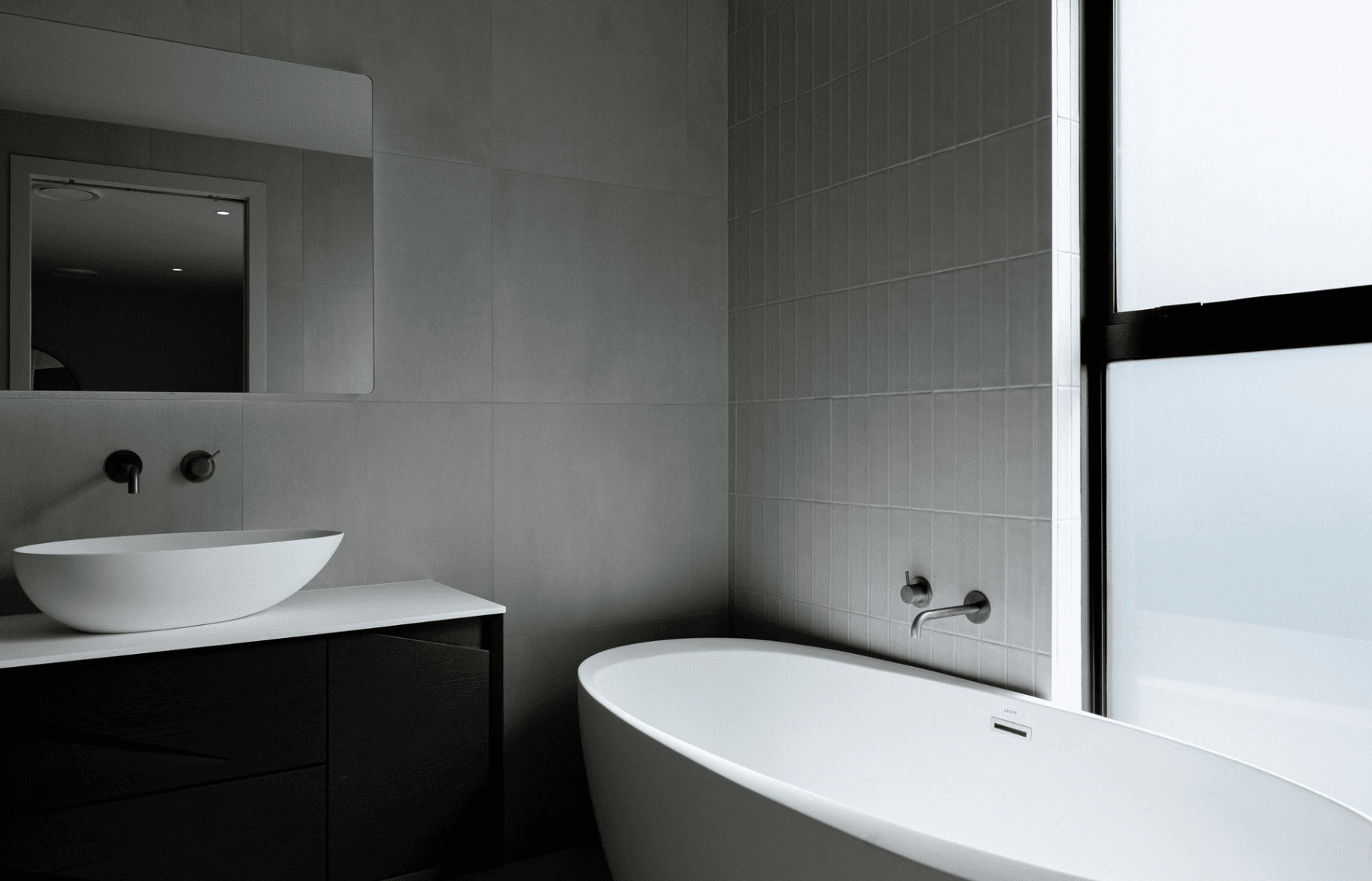 Sleek minimalist bathroom with vessel sink, black vanity, and freestanding tub