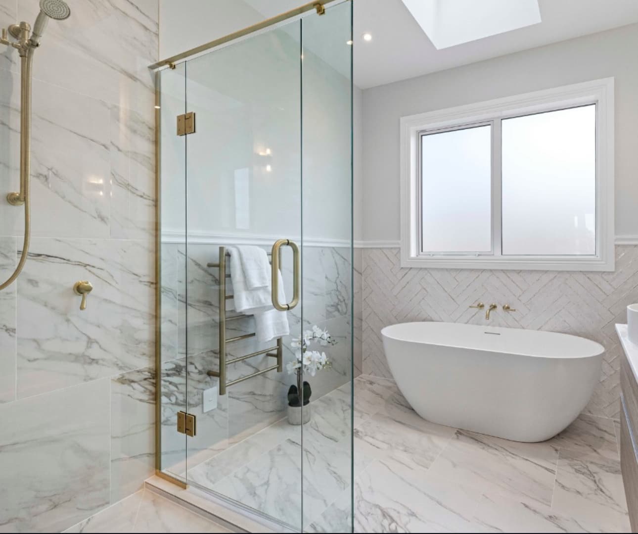 Luxury bathroom with marble tiling and glass shower enclosure